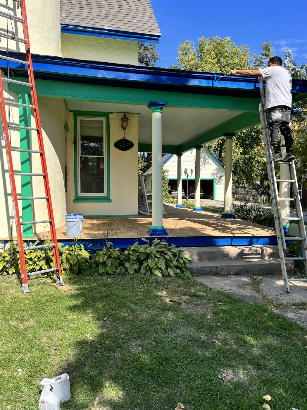 Painter on a ladder working on a porch ceiling and trim