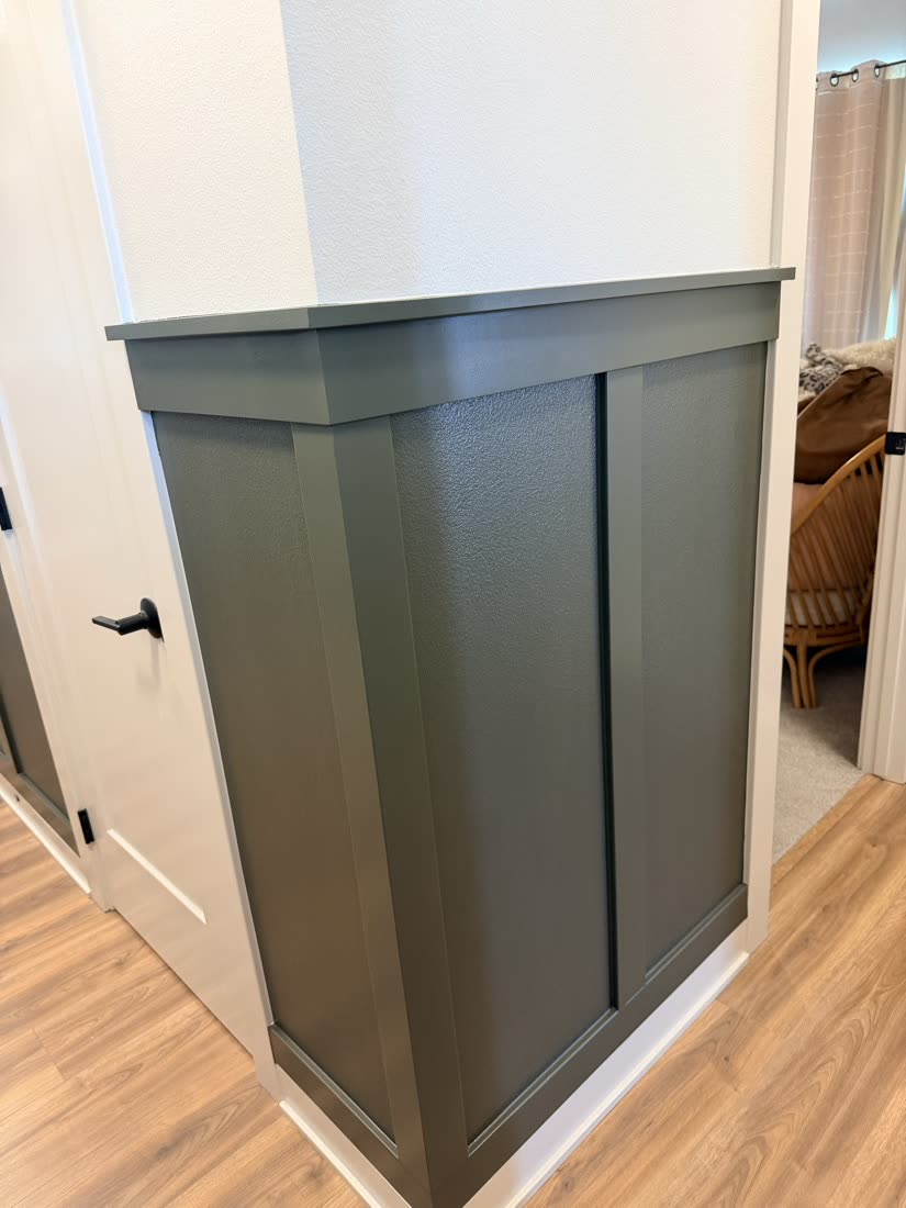 Close view of a painted gray-green wall panel corner with crisp edges