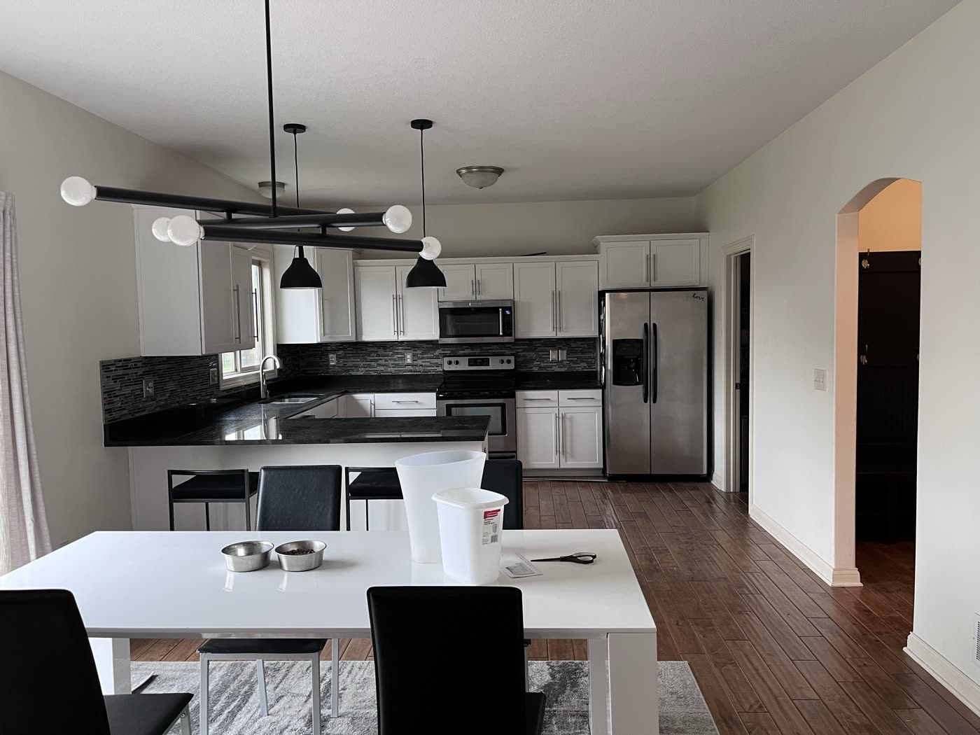Bright kitchen and dining area with white walls, white cabinets and wood floors