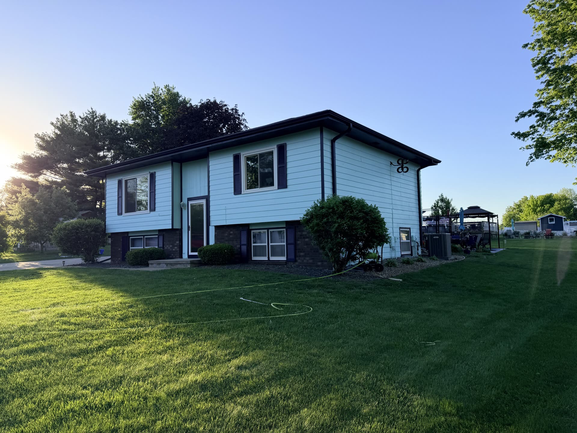 Light blue house with dark trim at the edge of a mown lawn